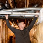 worker installing HVAC venting system